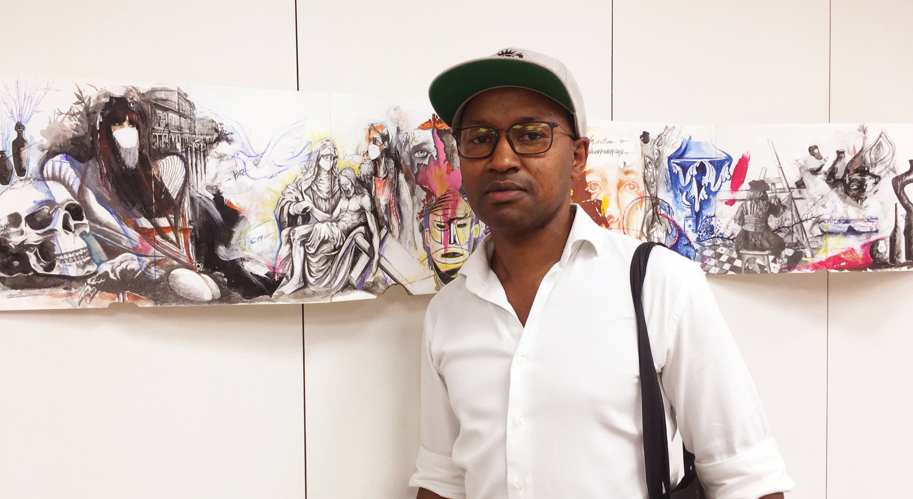 Cipriano Oquiniame standing in front of artistic wall displays